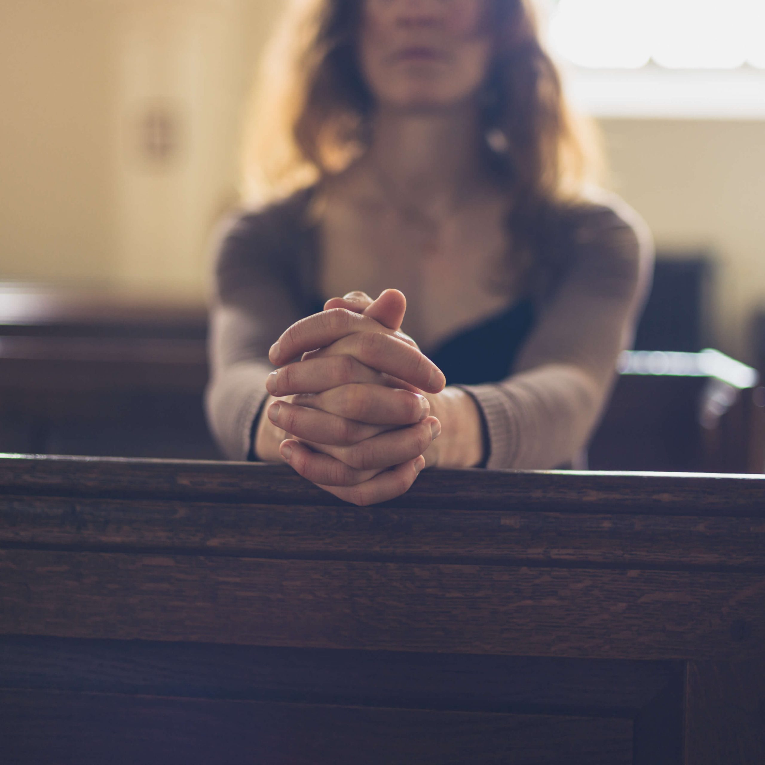 woman prays in church pew