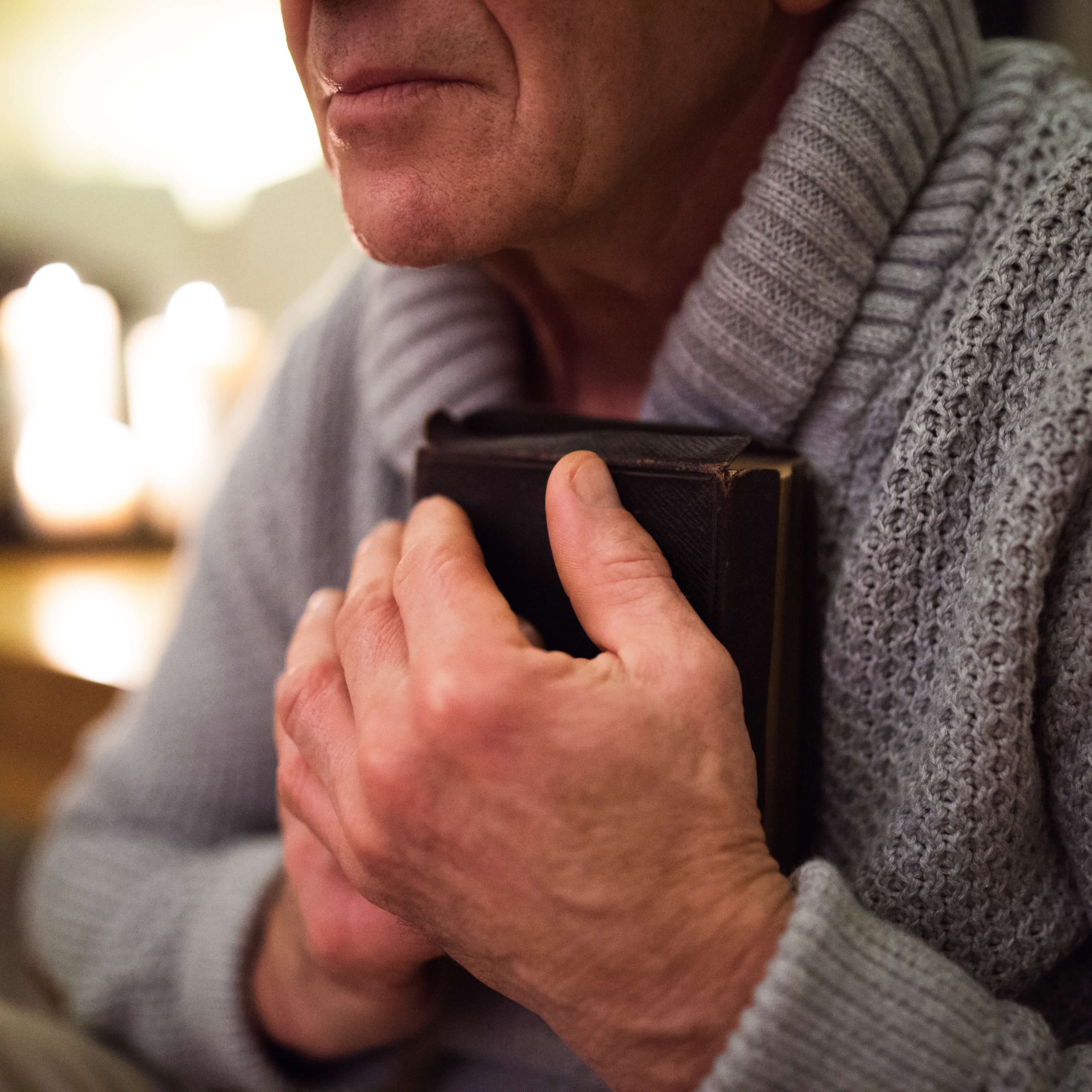 man clutches Bible in prayer