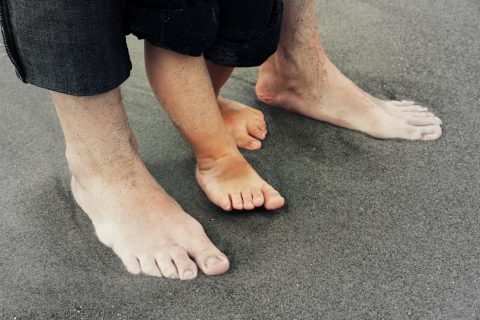 little feet with big feet on the beach
