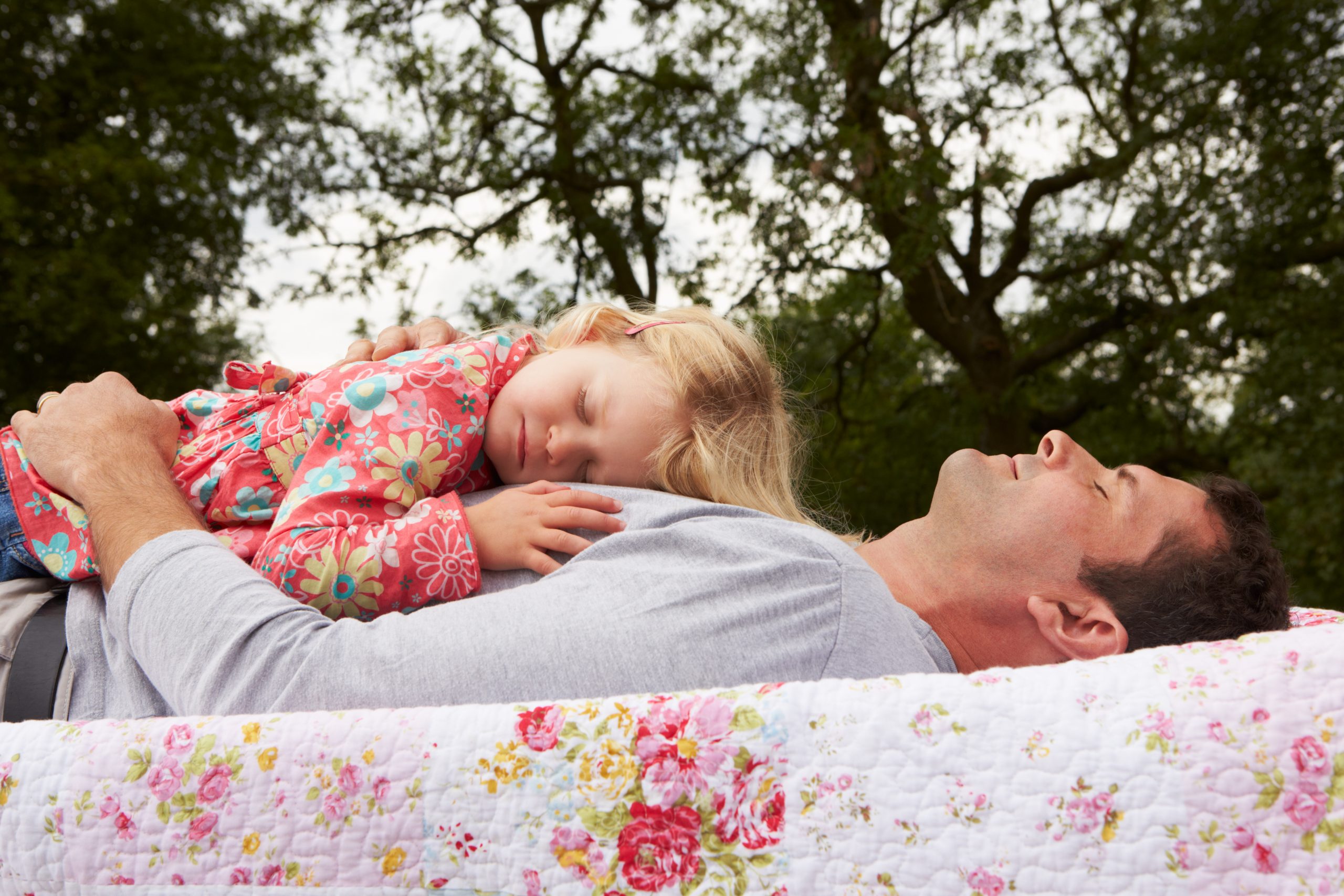 little blonde girl sleeps on daddy's chest