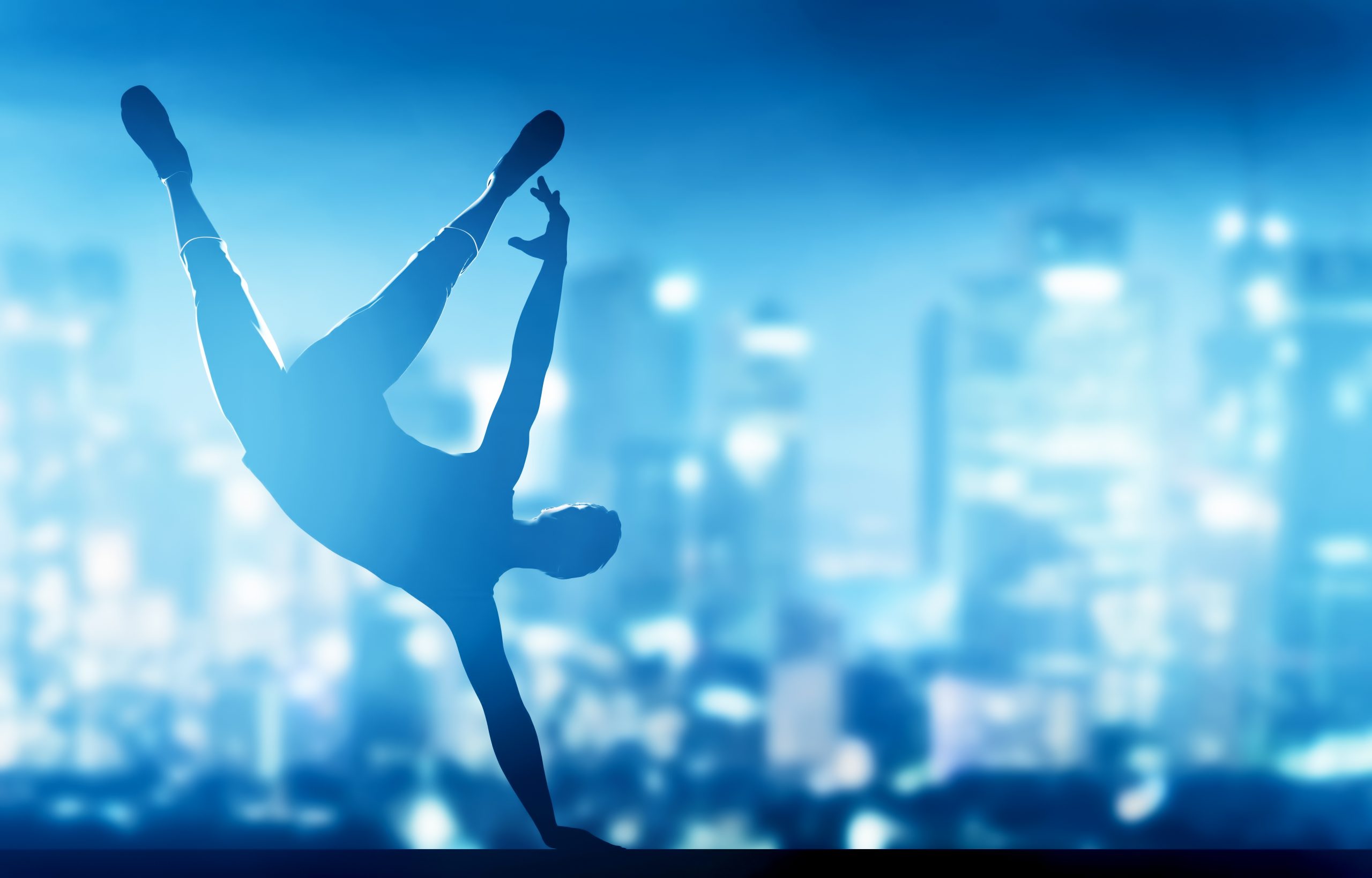 man somersaults on beam in front of a city (blue)