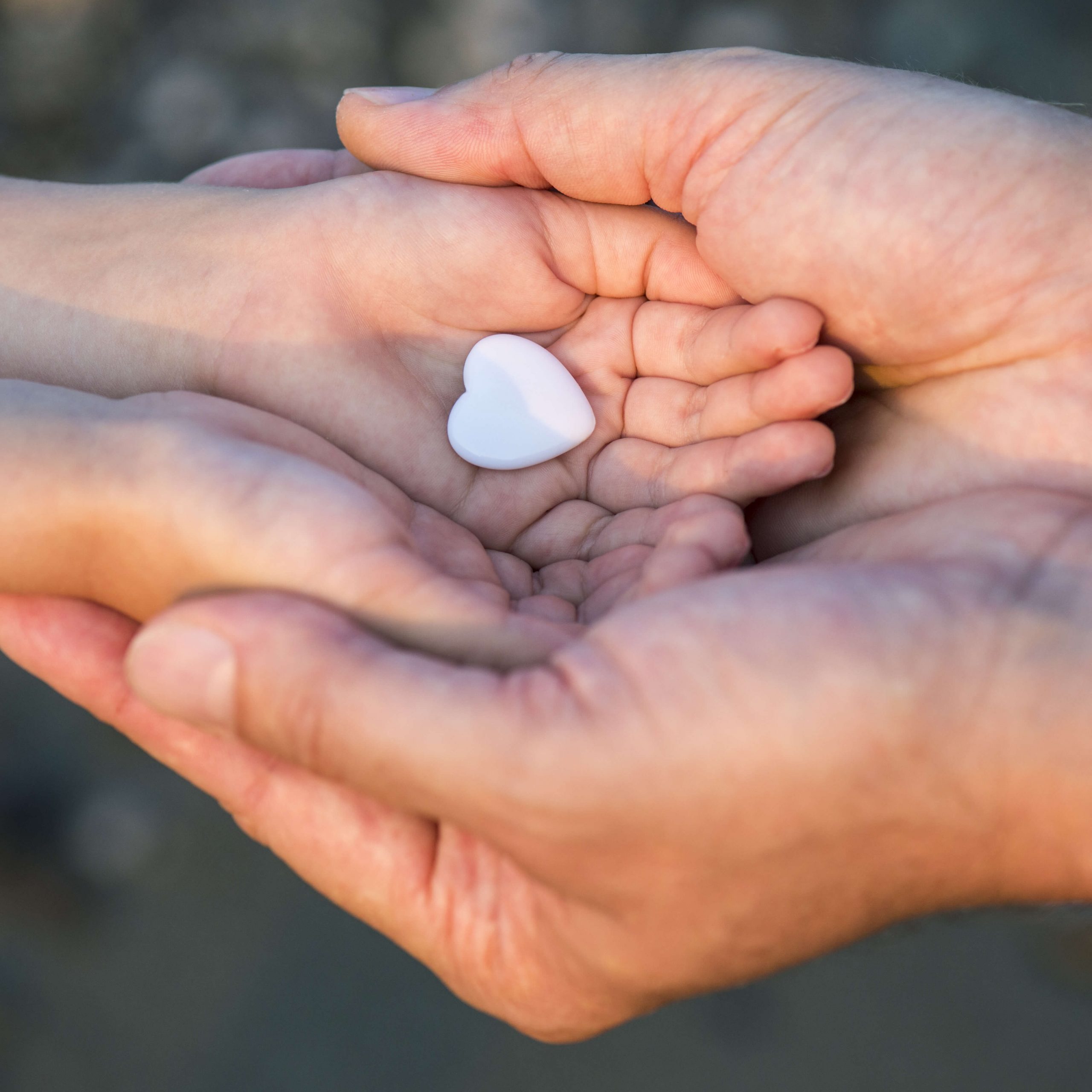 hand holding hand holding a white heart