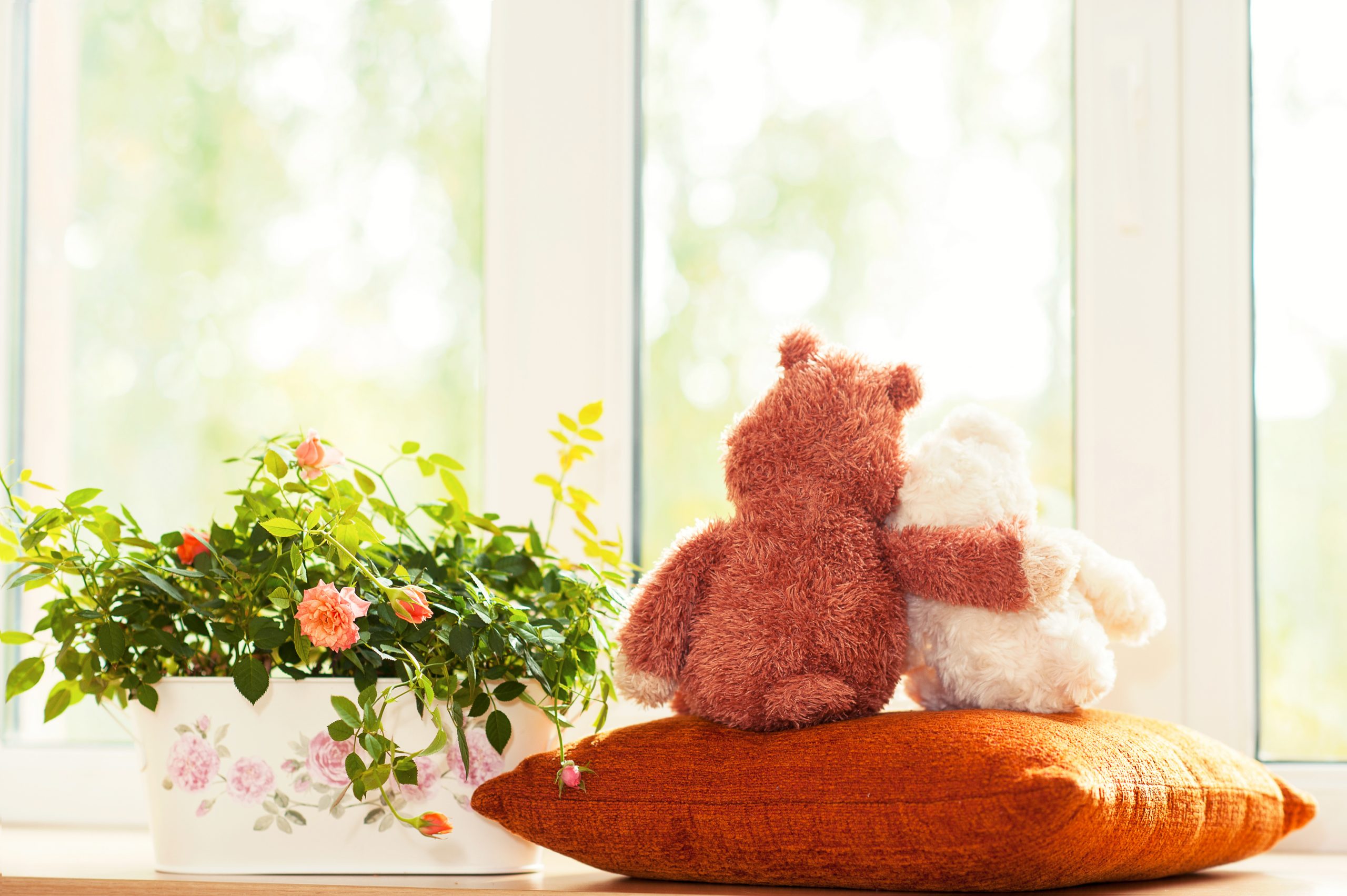 large teddy bear comforts small teddy bear on orange pillow