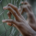 hands clutching fence